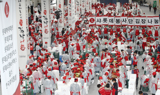 29일 오후 서울 양재동 aT센터에서 열린 '샤롯데봉사단 어울림 김장 나눔' 행사에서 롯데 계열사 임직원들이 김치를 담그고 있다. 롯데 임직원 1100여 명이 참여해 1만5000포기 김치를 만들어 전국 각지의 이웃들에게 전달할 예정이다.  연합뉴스